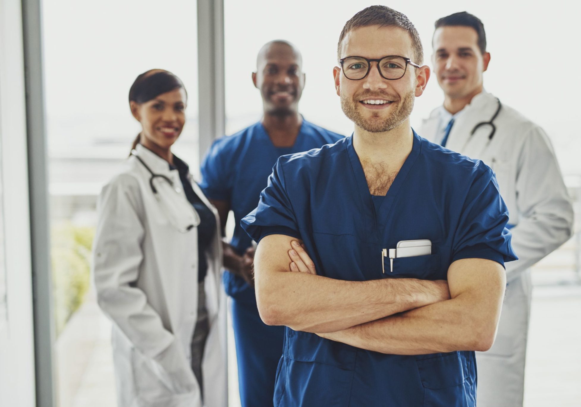 young male doctor standing in front of three other doctors